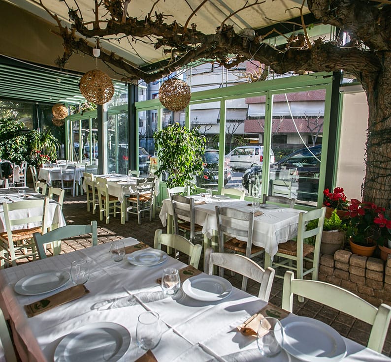 The covered courtyard: green chairs, white tablecloths, mulberry trunks and wicker lamps
