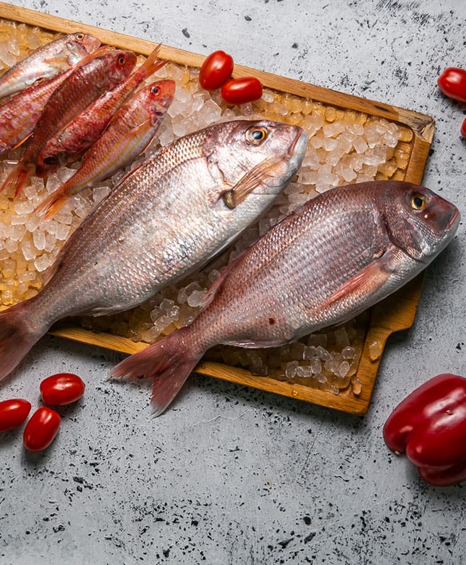 Two whole fish on crushed ice with cherry tomatoes