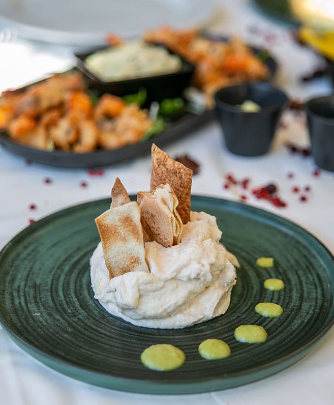 White taramosalata with crisp pita shards on a dark plate