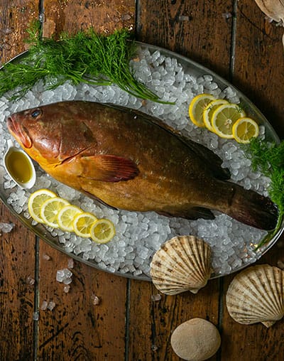 A whole fish on ice with lemon slices and dill
